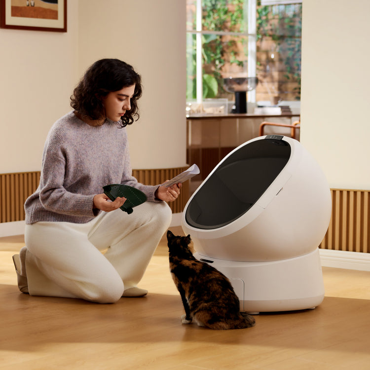 Petlibro automatic self-cleaning litter box in white with black lid, shown with a woman and a cat in a home setting