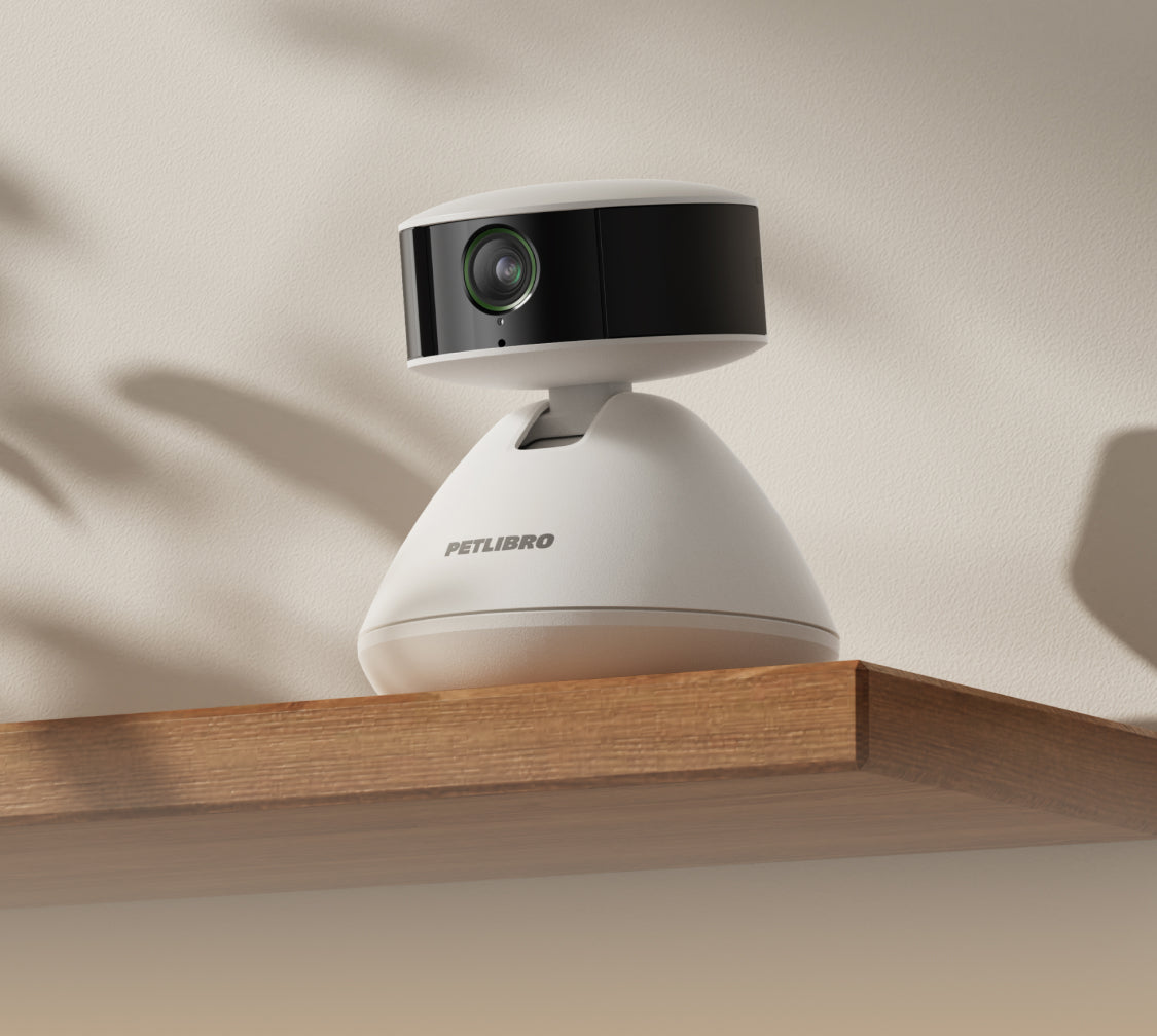 Petlibro white and black pet camera with wide-angle lens on wooden shelf for home pet monitoring