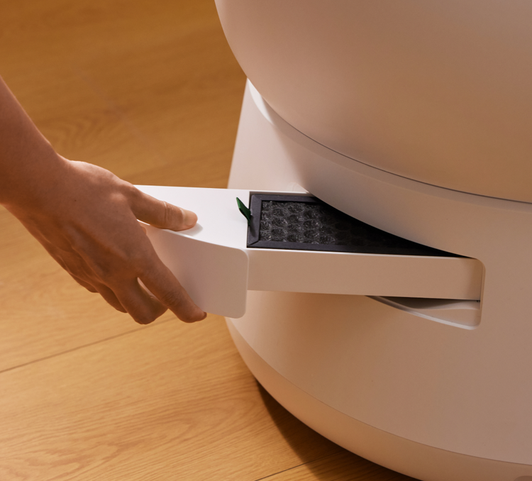 Petlibro automatic litter box with white pull-out drawer and black filter being handled on wooden floor