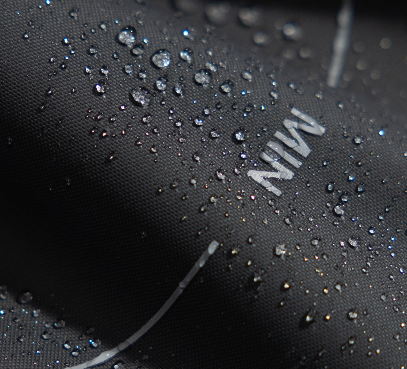 Petlibro close-up of black waterproof fabric with water droplets showcasing water resistance and durability
