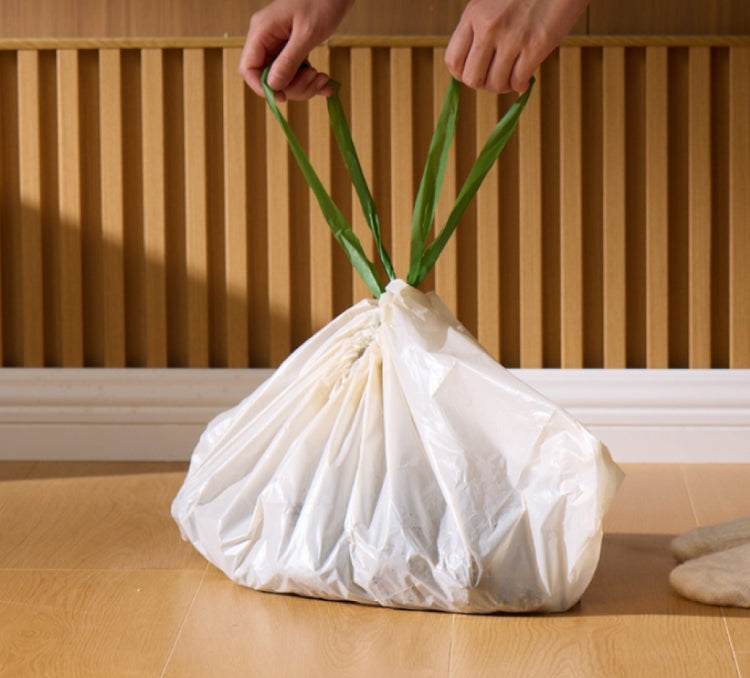 Petlibro white pet waste bag with green handles being lifted by hands on wooden floor background