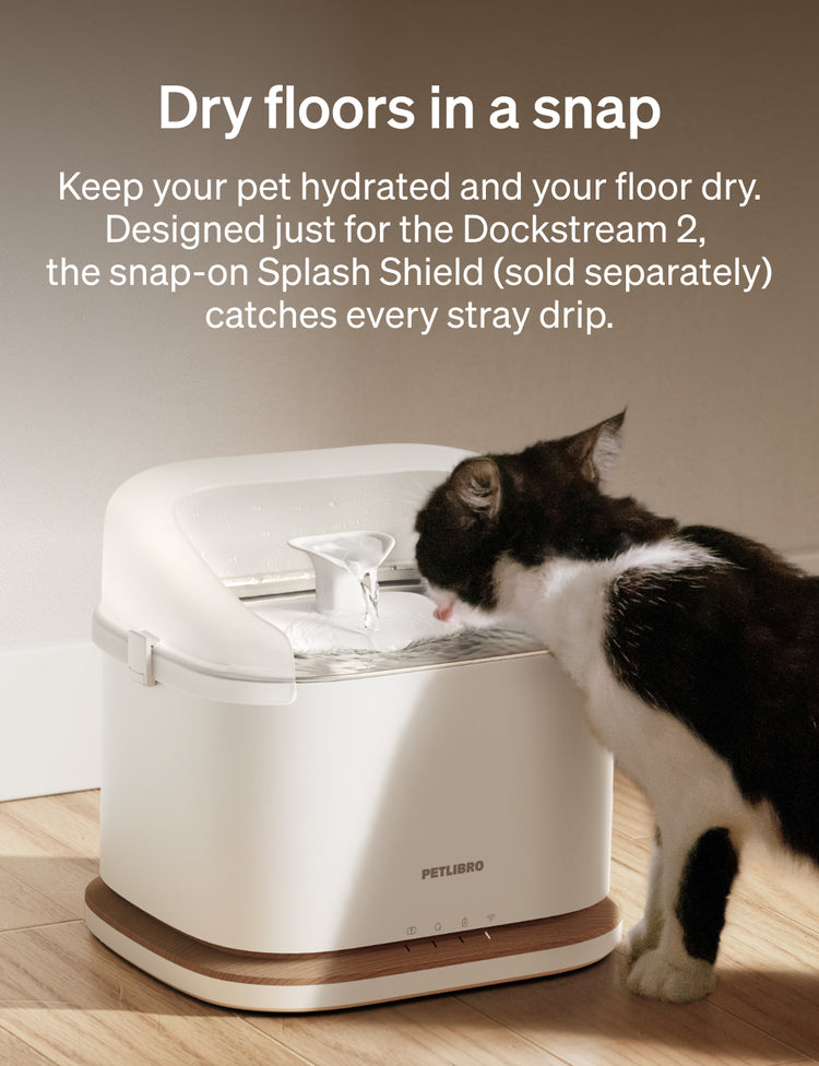 Petlibro PETLIBRO pet water fountain with splash shield; cat drinking beside it, not a litter box, on wood floor with text banner