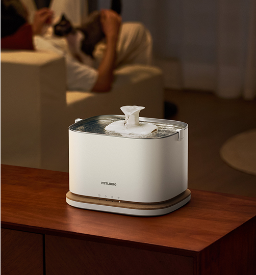 Petlibro PETLIBRO white pet water fountain on wooden table, flowing stream in cozy living room scene, not a litter box